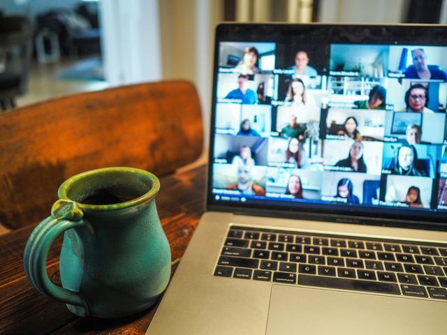 A laptop showing a video call with a full grid of remote colleagues