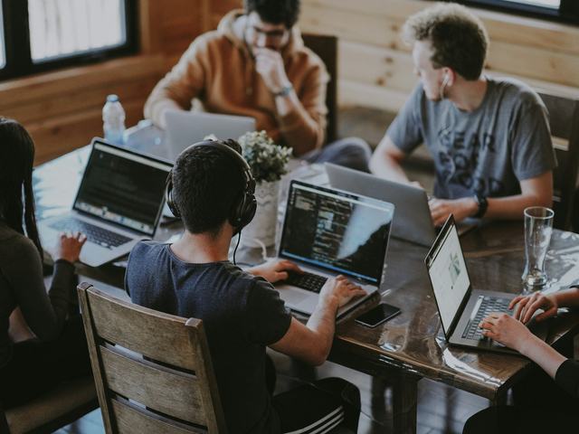 A small team working side by side on laptops around a shared table